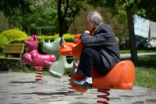 An elderly man sits on a hobby horse at a residential area in Beijing, May 4, 2015.