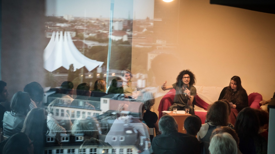 Syrian-Palestinian writer Ramy Al-Asheq talks at Muhannad's library in Berlin.