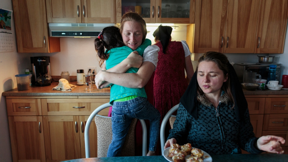 Elaine Hofer (à gauche) étreint Raghad, la fille aînée de la famille Al Hamoud, alors qu'Alice Hofer et Wanda Waldner préparent la nourriture pour les jeunes enfants. 