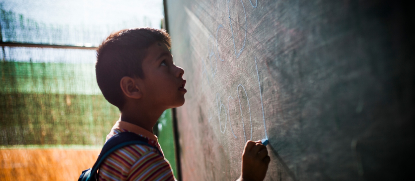 An Afghan boy spells out the Roman alphabet at a special English-language class at the Oinofyta reception centre in Greece.