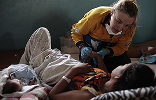 A health care worker helping a mother with her new born, in Ecuador