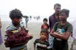 A Rohingya man carries an infant born while his family was hiding in t...