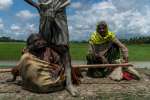 Rohingya refugee Mabia Khatun, 75, (left) rests after being carried to...