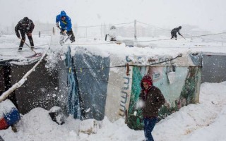 Syrian refugees remove snow from their shelters at an informal tented settlement in the Bekaa Valley, Lebanon during a blizzard earlier today. © UNHCR/A.McConnel