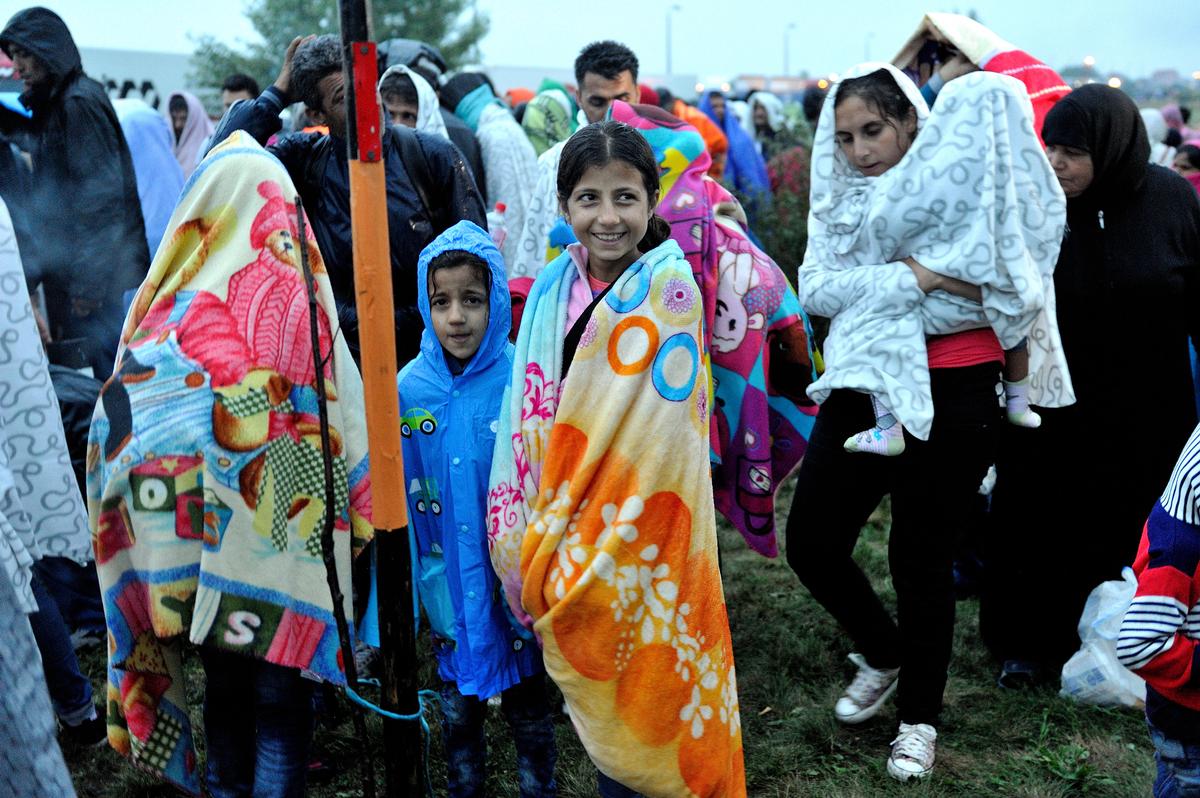 Syrian children warm themselves with colourful blankets