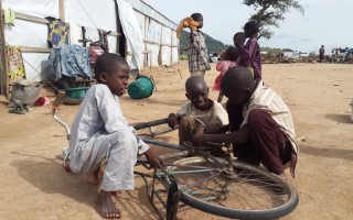 Refugee children repair a bicycle at Minawao camp in Cameroon, 2015 file photo. © UNHCR/D. Mbaiorem