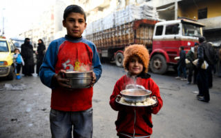 Displaced children carry cooked meals provided by a local charity in the Al-Mashatiyeh neighborhood of east Aleppo, Syria, where UNHCR and its partners are distributing key relief items.   © UNHCR/Bassam Diab