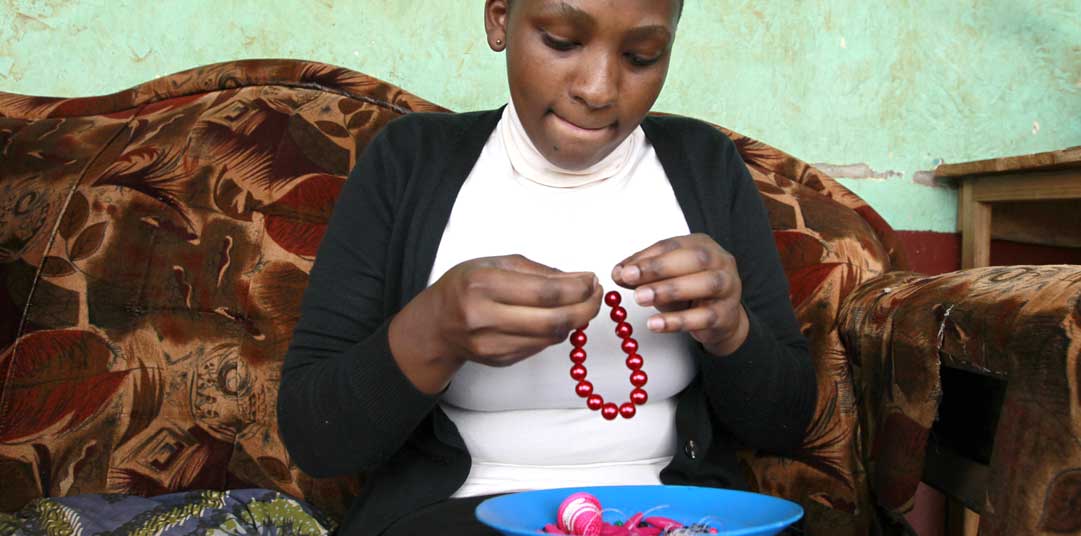 A young woman makes works on her keyrings as part of the ‘Keyring Project’ in Kampala, Uganda