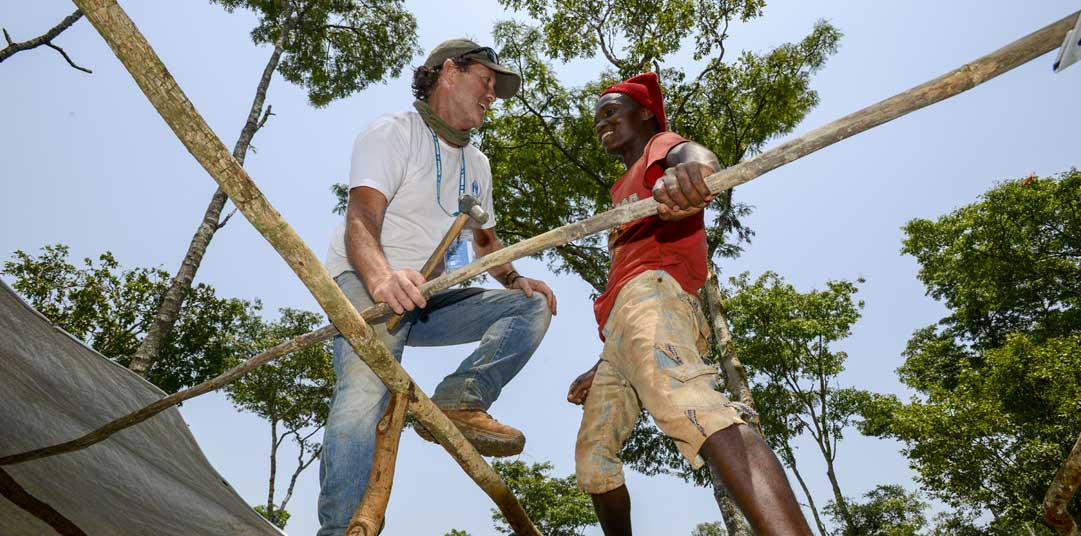 UNHCR shelter expert Tom Corcoran helps a refugee construct a temporary home in Tanzania