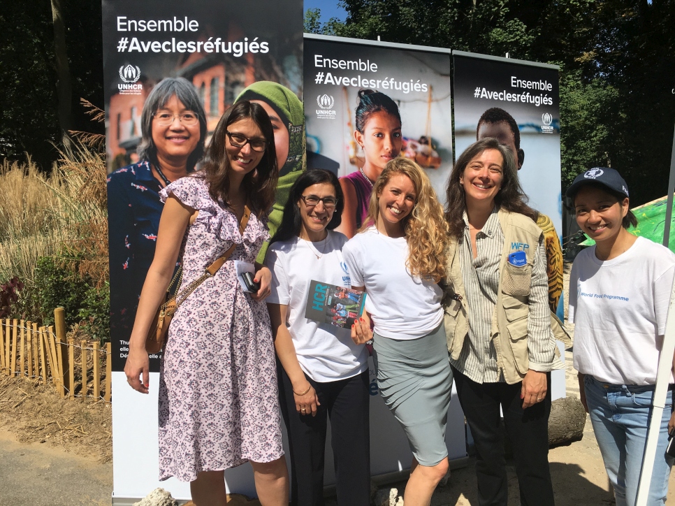 L'équipe du HCR France, du PAM et une journaliste posent en face de banderoles de la pétition #Aveclesréfugiés au Domaine de Longchamp à Paris lors d'un week de sensibilisation sur la situation des réfugiés le 18 juin 2017.