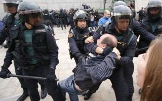  Spanish Guardia Civil guards drag a man outside a polling station in Sant Julia de Ramis