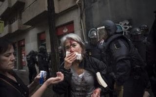 A woman tends to her injuries in front of riot police near a school being used as a polling station 