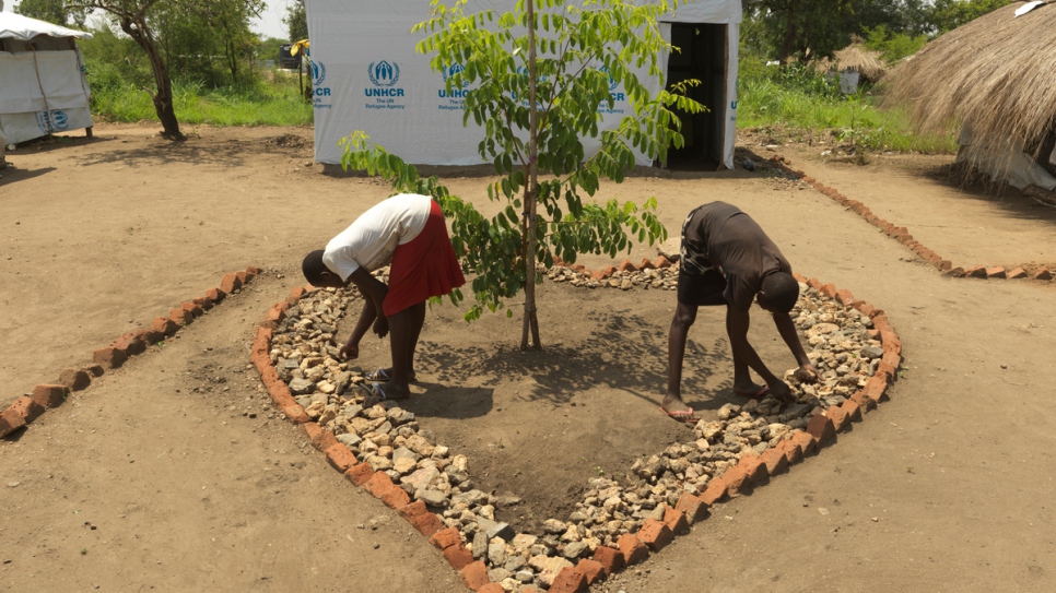 Tabu (right) makes a rock garden with her twin sister outside their shelter.