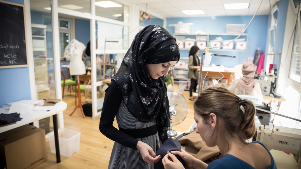 Seamstress Anna Kossmann helps Esraa in the workshop.