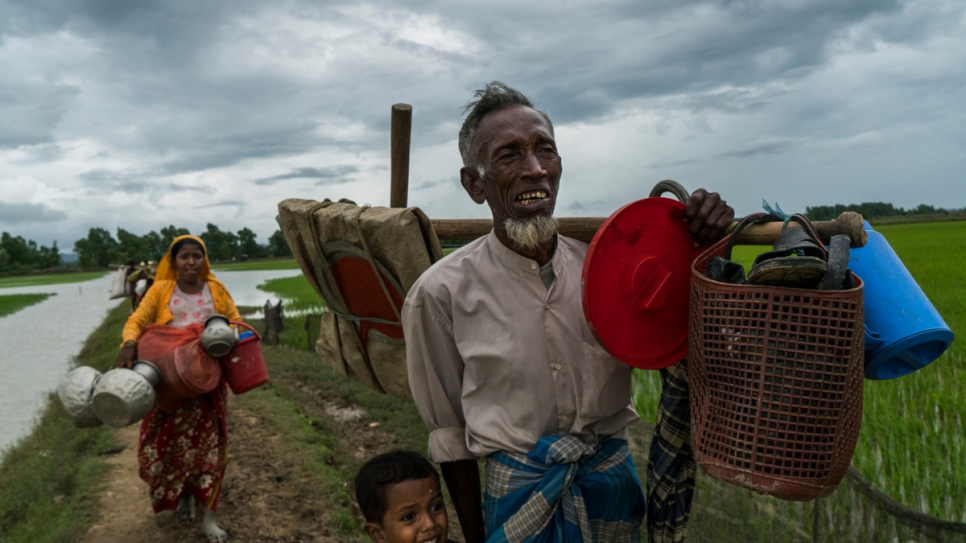 Imran Hussain (right) weeps as he leads his grandson and daughter Senwara Begum (left) after crossing the border from Myanmar into Bangladesh near Whaikhyang.