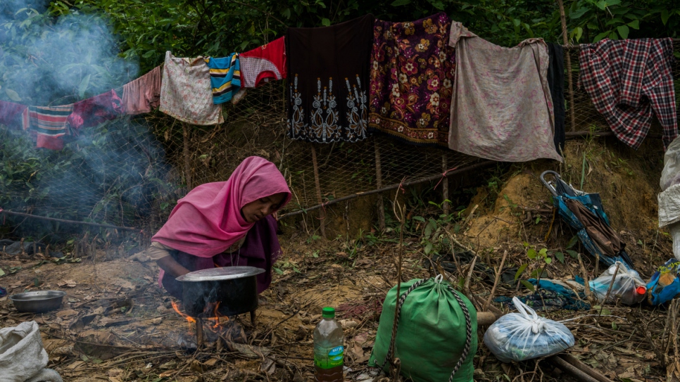 A Rohingya refugee tries to start a fire to cook rice she begged from a local family, on the side of the road near Thangkali settlement in, Bangladesh. She arrived in Bangladesh eight days earlier with her husband and five children.