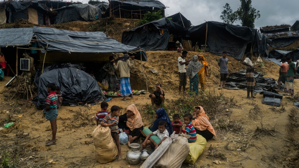 A Rohingya refugee family waits as they seek a space to live at an informal settlement in Thangkali, Bangladesh. 