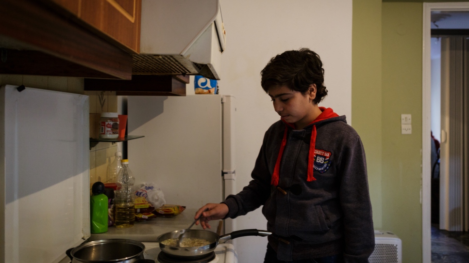 Fourteen-year-old Samir cooks in the kitchen of his family's shared accommodation.