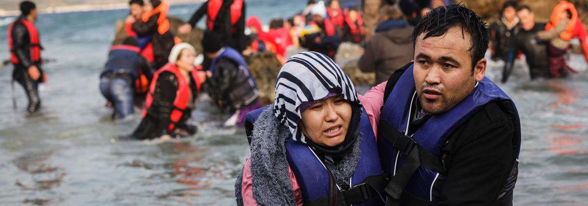 A refugee from Afghanistan helps his wife out of the sea, after the inflatable boat they used to cross part of the Aegean from the coast of Turkey to Greece crashed on a rock off the coast of Lesbos island.