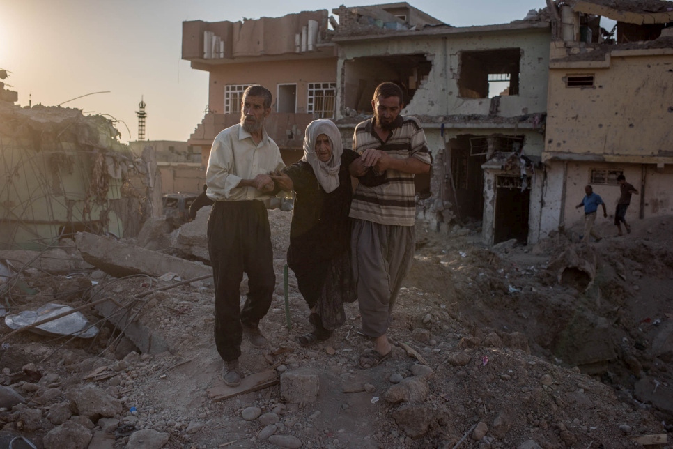 Two men help an elderly woman flee Mosul, Iraq on June 24, 2017.