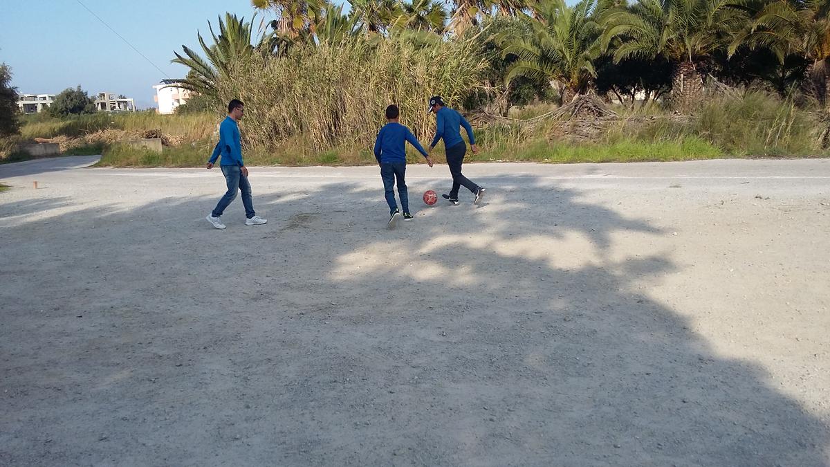 Unaccompanied Afghan refugee Samir, aged 14, plays football with friends at a transit facility on Kos.