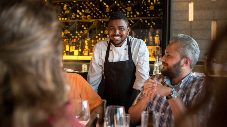 Le chef somalien Hassan Hassan discute avec des clients venus goûter son menu dans le restaurant Vassilenas à Athènes. 