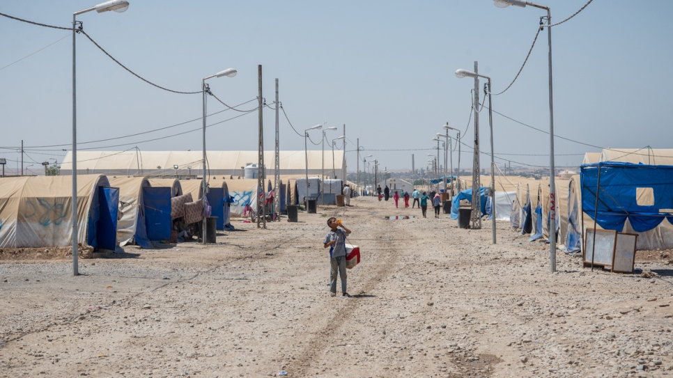 A young boy walks along a main road at Hammam Al-Alil camp.