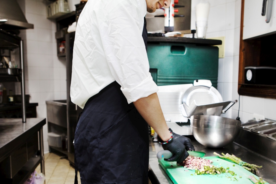 Tareq travaille dans la cuisine d'un restaurant local pour acquérir de l'expérience et se faire des amis. 