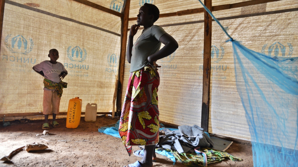 Charlene stands in her new shelter with her son at Mahama refugee camp.