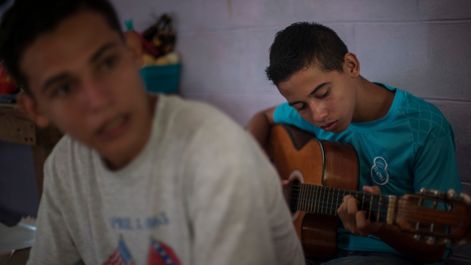 Anderson plays guitar in the room where he lives with his two brothers.