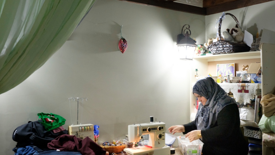 Rabiaa uses a sewing machine to adjust an item of clothing for a client. 