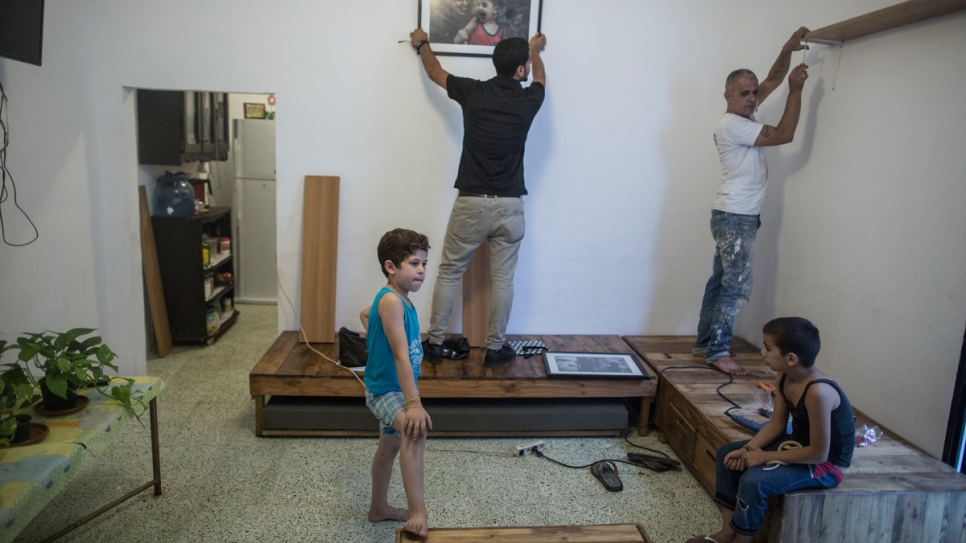 Decorators hang shelves and photographs in Haela's newly renovated home.