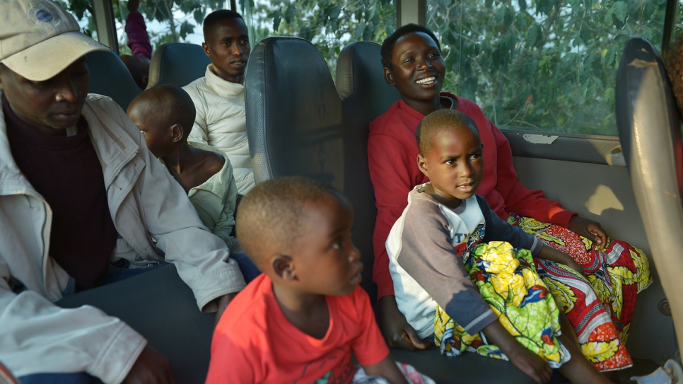Charlene sits in a UNHCR-chartered bus along with her husband (behind) and their two children.