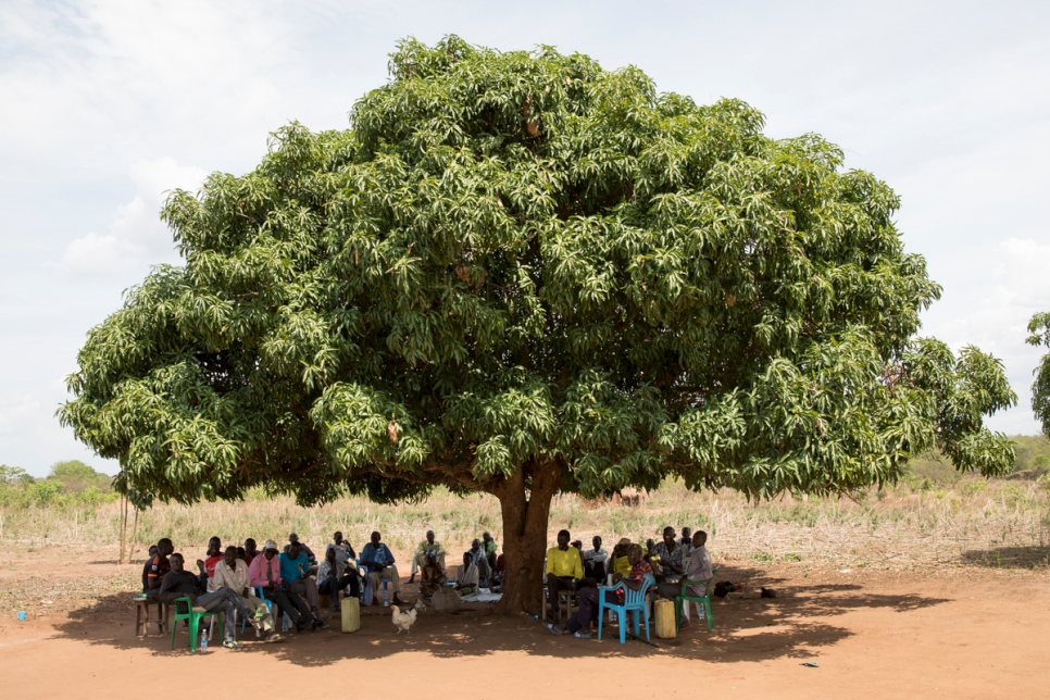 Ugandan residents and South Sudanese refugees meet on the farm of Ugandan farmer Yahaya Onduga in Bidibidi. Yahaya has given some of his land to refugees as part of an official donation process and also allows other refugee families to grow crops on other plots.  