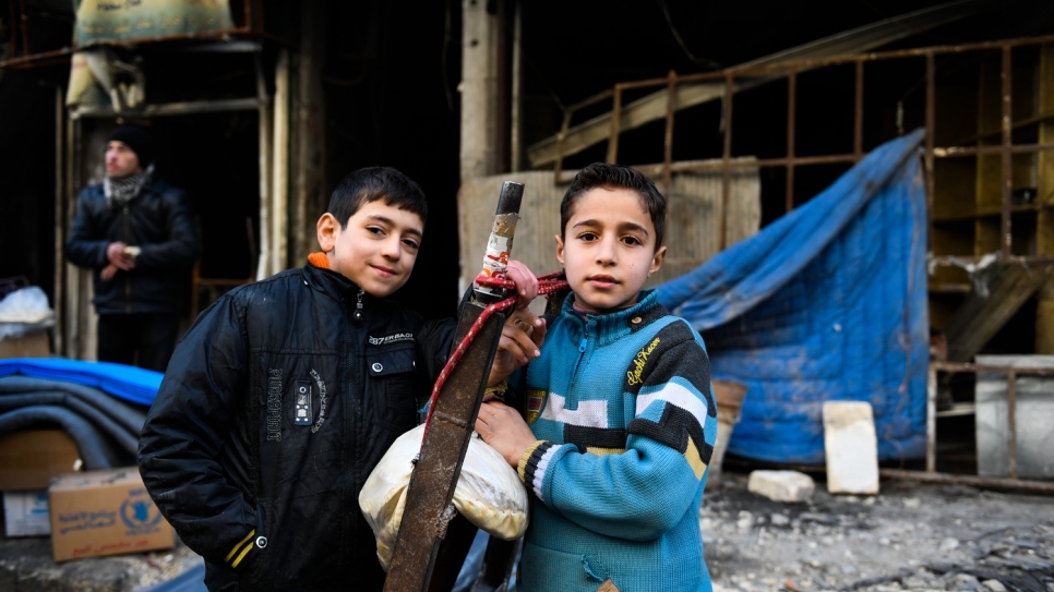 طفلان يقفان أمام مبنى مدمر في حي المشاتي في شرق حلب.