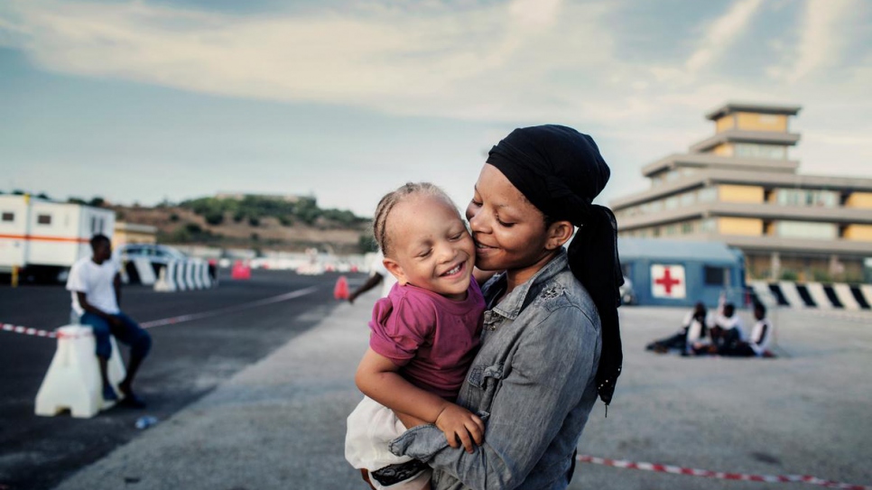 Nigerian refugee Shalom, 24, hugs her young daughter after being rescued at sea and taken to the Italian port of Augusta. 