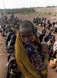 A Somali girl holds a child while waiting for food distribution in a Baidoa refugee camp December 11, 1992.