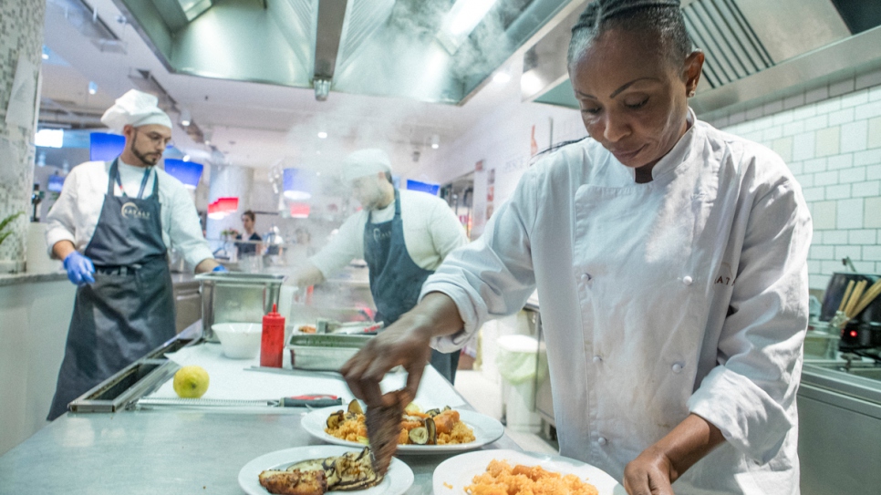 Rita, a refugee from the Democratic Republic of Congo, prepares a fish dish in the kitchen of Eataly in Milan.