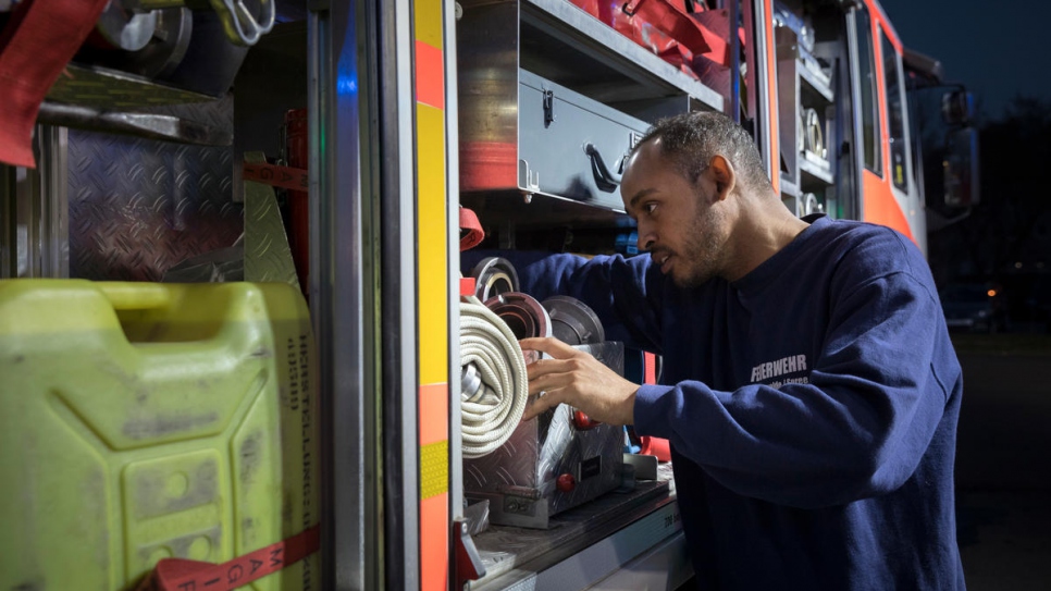 Yusuf checks the equipment on a fire truck. Volunteer firefighters like him come to the station in Fürstenwalde for training once a week.