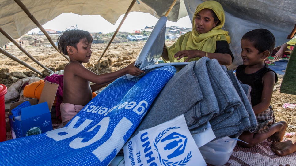 Laila Begum, 30, and her children open an aid pack – including a solar lantern, phone charger, blankets, tarpaulin and kitchen set – at Kutupalong refugee camp on November 20.