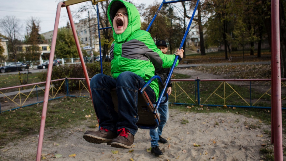Igor roars with delight on the swing as his father, Gesha, looks on.