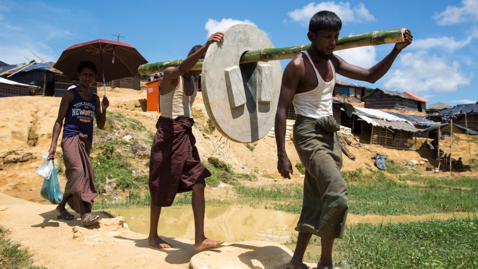 UNHCR's Bangladeshi partners take sections of concrete pipe to build latrines into the camp extensions on bamboo poles.