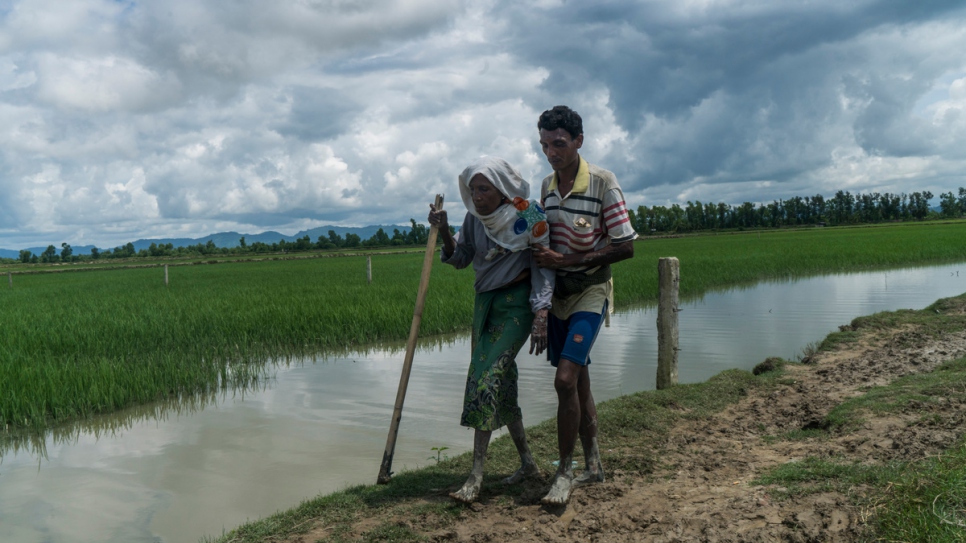 Azala Khatun, 70 ans, une réfugiée rohingya, est aidée par l'un de ses fils après avoir traversé la frontière depuis le Myanmar près de Whaikhyang, au Bangladesh. 