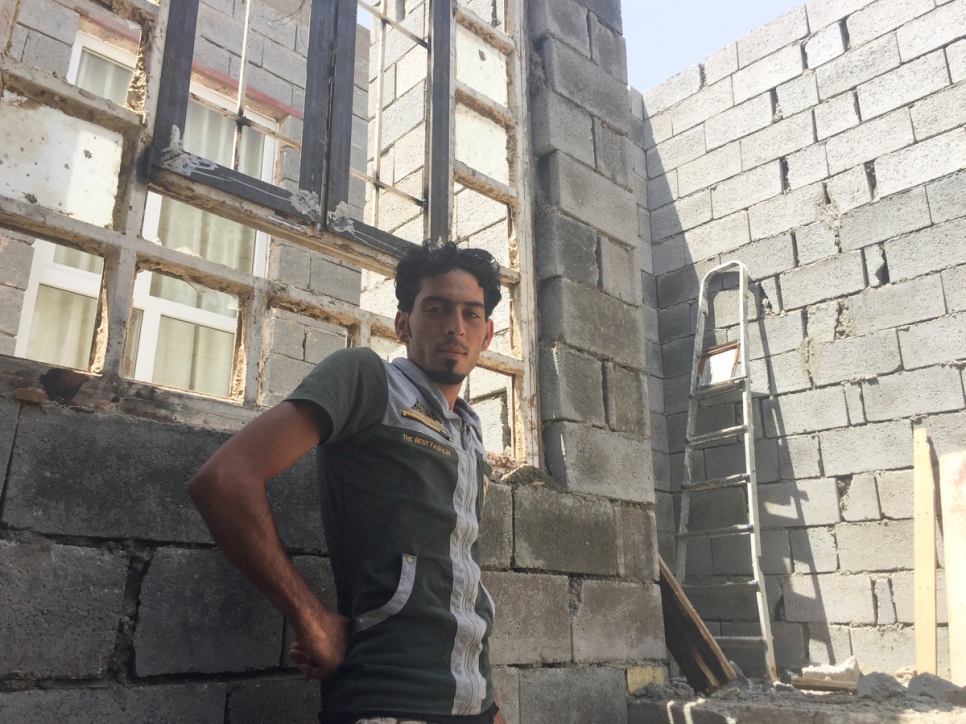 يقف إبراهيم خليل، 25 عاماً، عامل وسائق رافعة، بالقرب من نافذة مكسورة في منزله – الذي تدمر سقفه. 