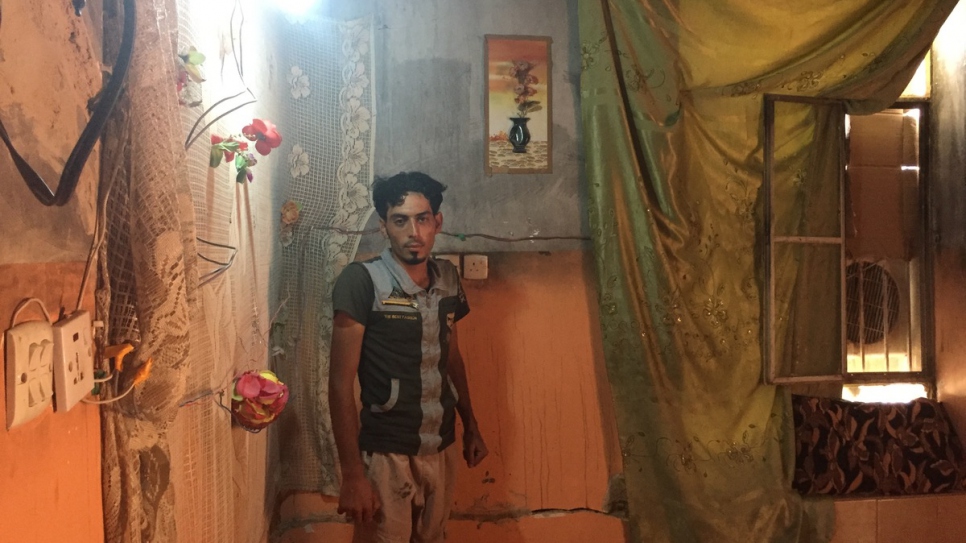 Ibrahim Khalil, ouvrier de 25 ans et conducteur de grue, se trouve près d'une fenêtre cassée dans sa maison - le toit est ouvert sur le ciel.