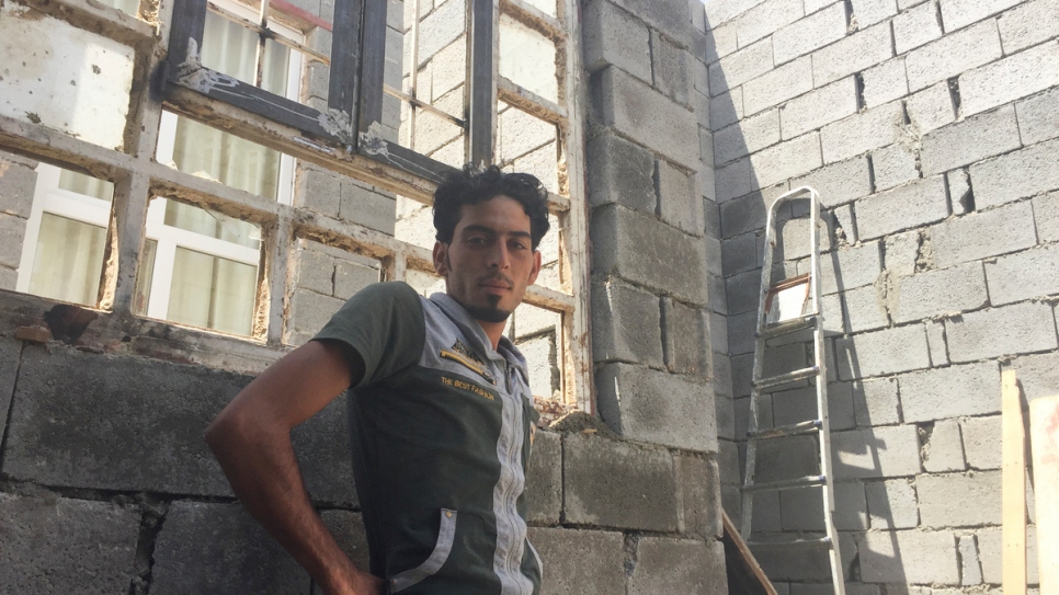 Ibrahim Khalil, ouvrier de 25 ans et conducteur de grue, se trouve près d'une fenêtre cassée dans sa maison - le toit est ouvert sur le ciel.