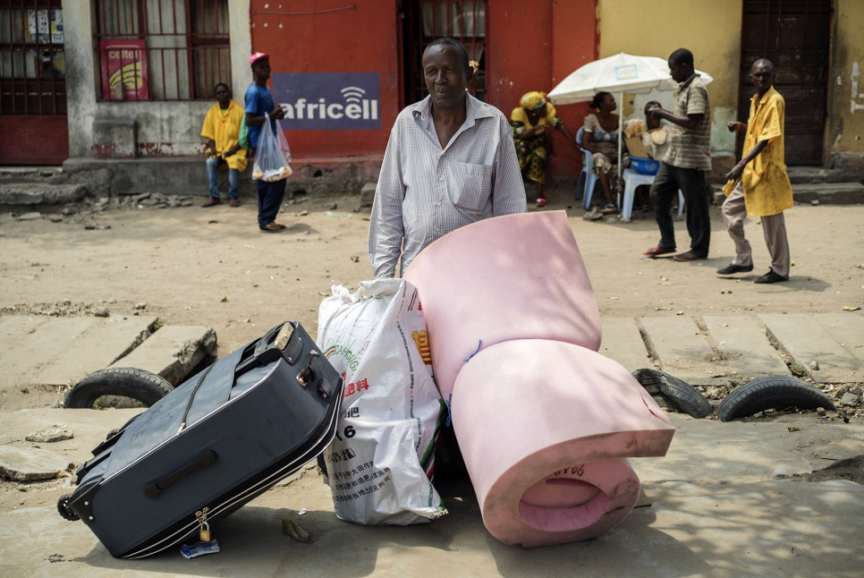 Theophile, 66, waits for assistance with his luggage at a collection point in Kinshasa, DRC. After decades in exile, he is finally going home.