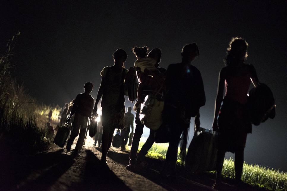 Former Angolan refugees carry their belongings to a transit site after disembarking from a train that has brought them from Kinshasa, DRC. A bus will take them to the Angolan border.