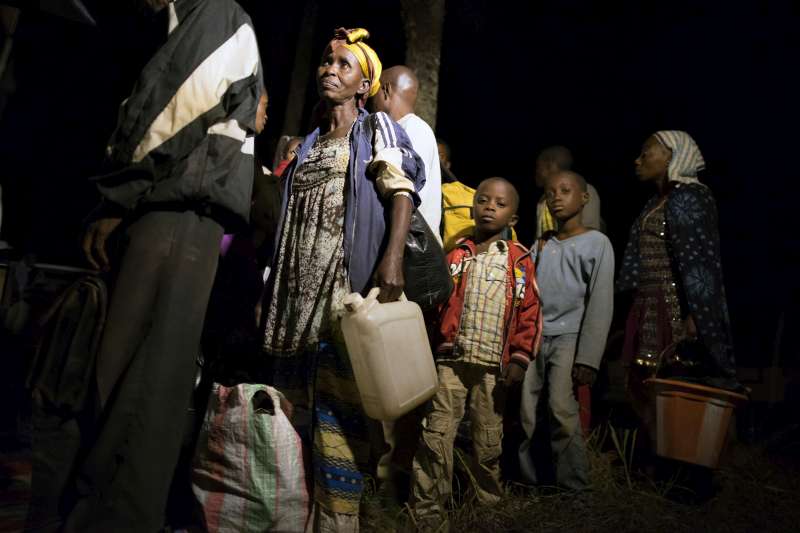 Maria, carrying a plastic jerry can, prepares to board a bus for the final border crossing after having her documents checked by the Angolan authorities. 