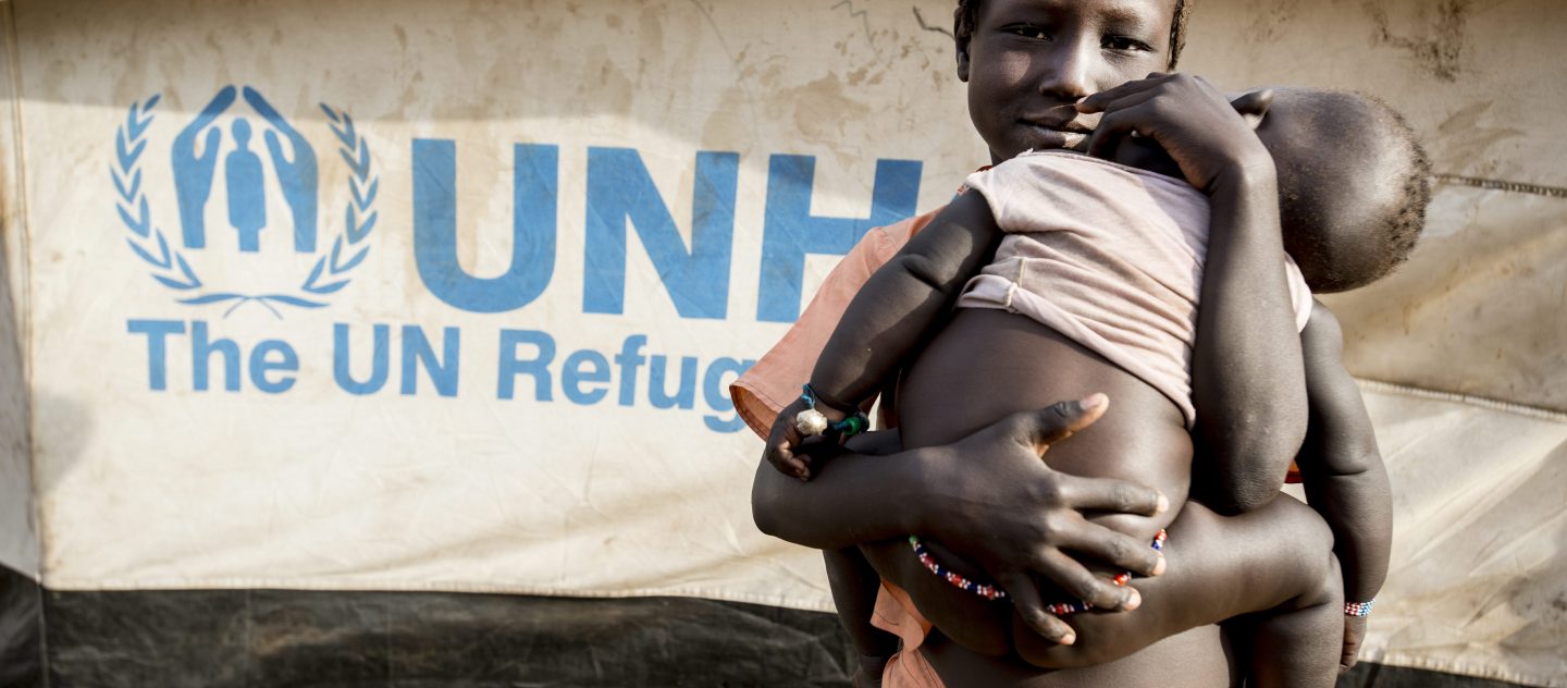 'Ung Sydsudansk pige bærer hendes bror i UNHCR's flygtningelejr, Doro, i Mabaan, Sydsudan.